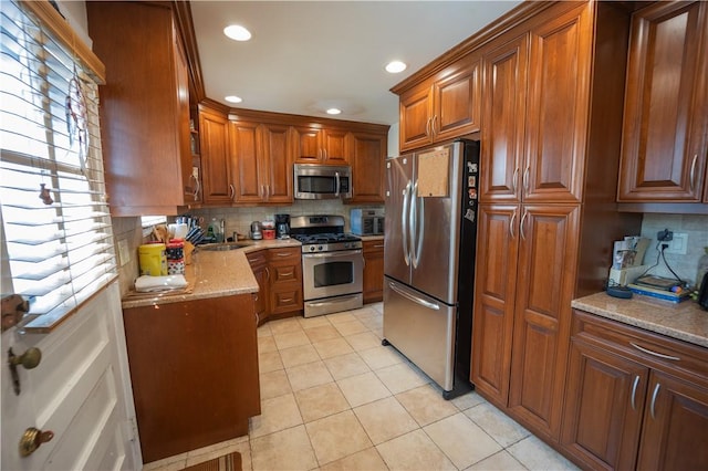 kitchen featuring sink, stainless steel appliances, tasteful backsplash, light stone counters, and light tile patterned floors