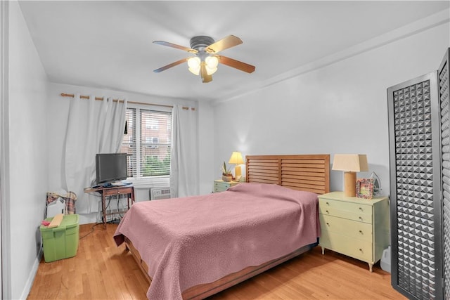 bedroom with a wall mounted AC, ceiling fan, and light hardwood / wood-style flooring