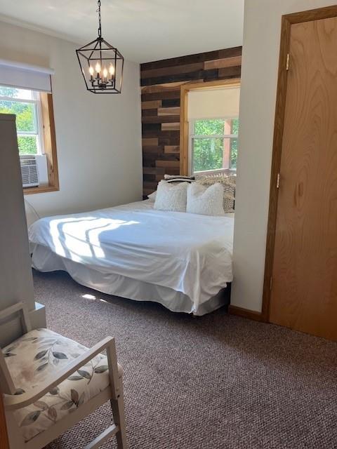 bedroom featuring carpet flooring, a notable chandelier, and wood walls