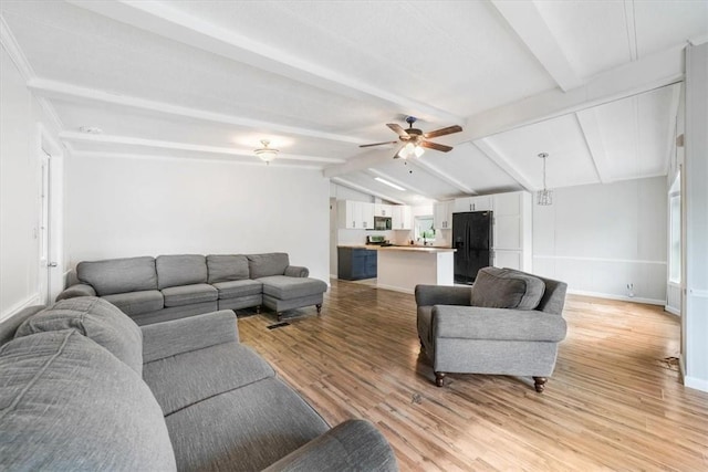 living room with ceiling fan, lofted ceiling with beams, and light wood-type flooring