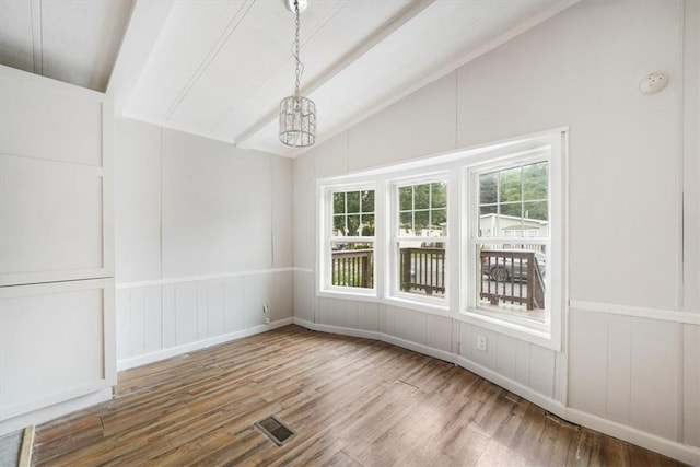 unfurnished dining area featuring hardwood / wood-style flooring, a notable chandelier, a wealth of natural light, and vaulted ceiling