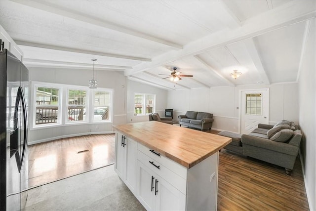 kitchen featuring lofted ceiling with beams, black fridge, white cabinetry, and wooden counters