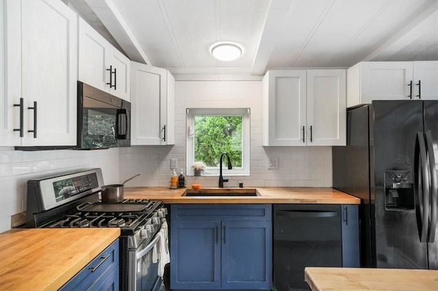 kitchen featuring blue cabinets, sink, black appliances, butcher block countertops, and white cabinetry