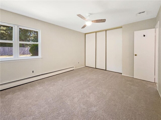 unfurnished bedroom featuring ceiling fan, a closet, a baseboard radiator, and light carpet