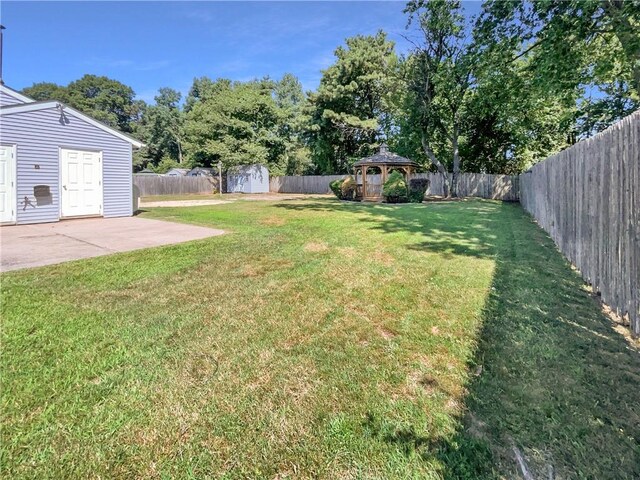 view of yard featuring a gazebo, a storage shed, and a patio