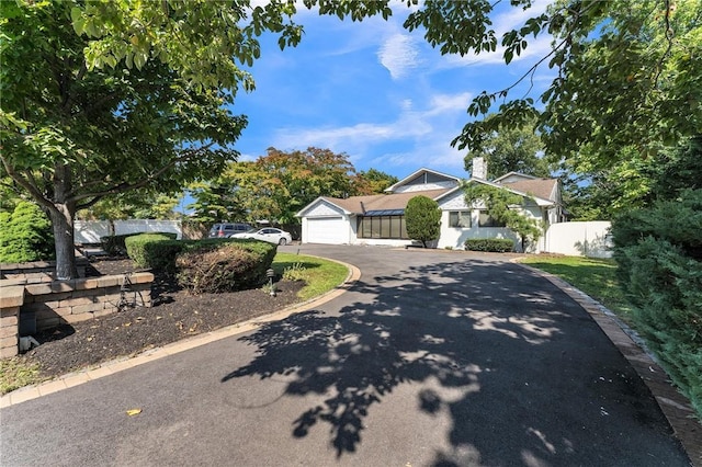 view of front of house featuring a garage, aphalt driveway, and fence