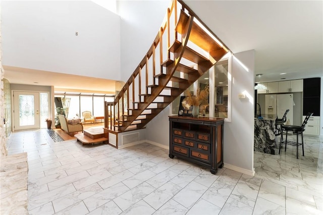 entryway with marble finish floor, baseboards, and stairs