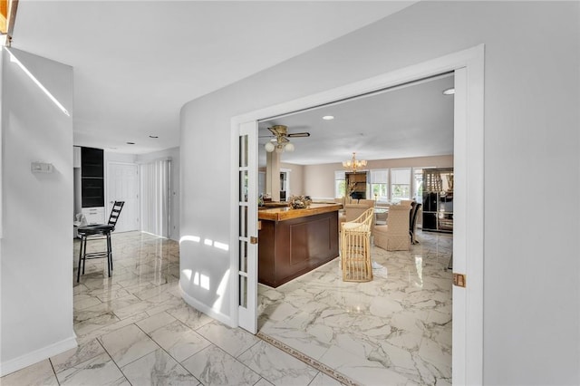 interior space featuring marble finish floor, recessed lighting, wooden counters, an inviting chandelier, and baseboards