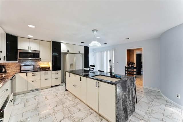 kitchen featuring marble finish floor, stainless steel microwave, backsplash, and a sink