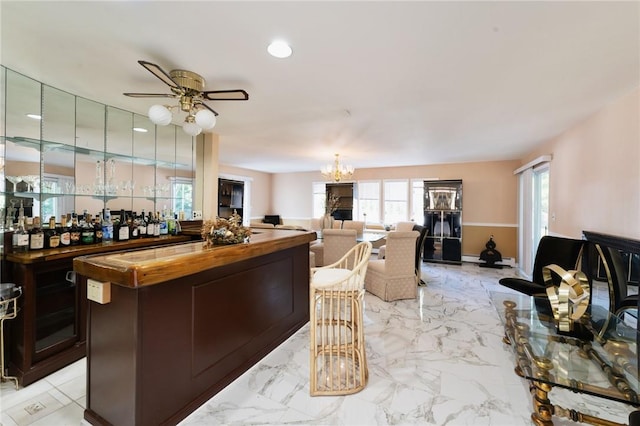 bar featuring marble finish floor, baseboards, a dry bar, and ceiling fan with notable chandelier