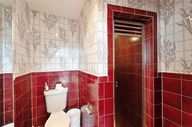 bathroom with toilet, a shower stall, and tile walls