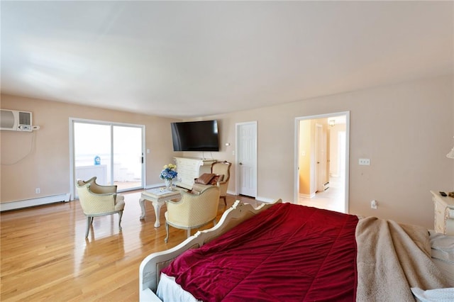 bedroom with a wall mounted air conditioner, baseboards, baseboard heating, and wood finished floors