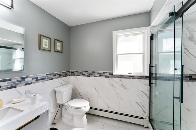 bathroom with a marble finish shower, toilet, baseboard heating, vanity, and tile walls