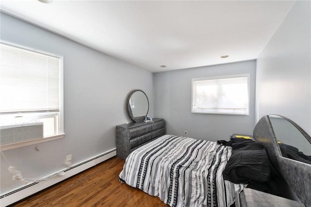 bedroom with a baseboard heating unit and wood finished floors