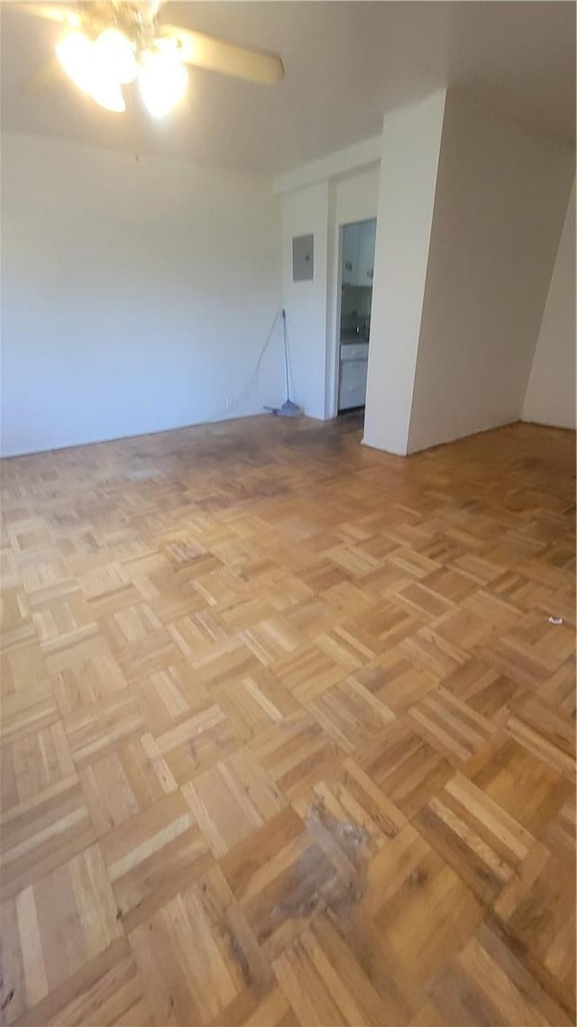 empty room featuring ceiling fan, electric panel, and light parquet flooring