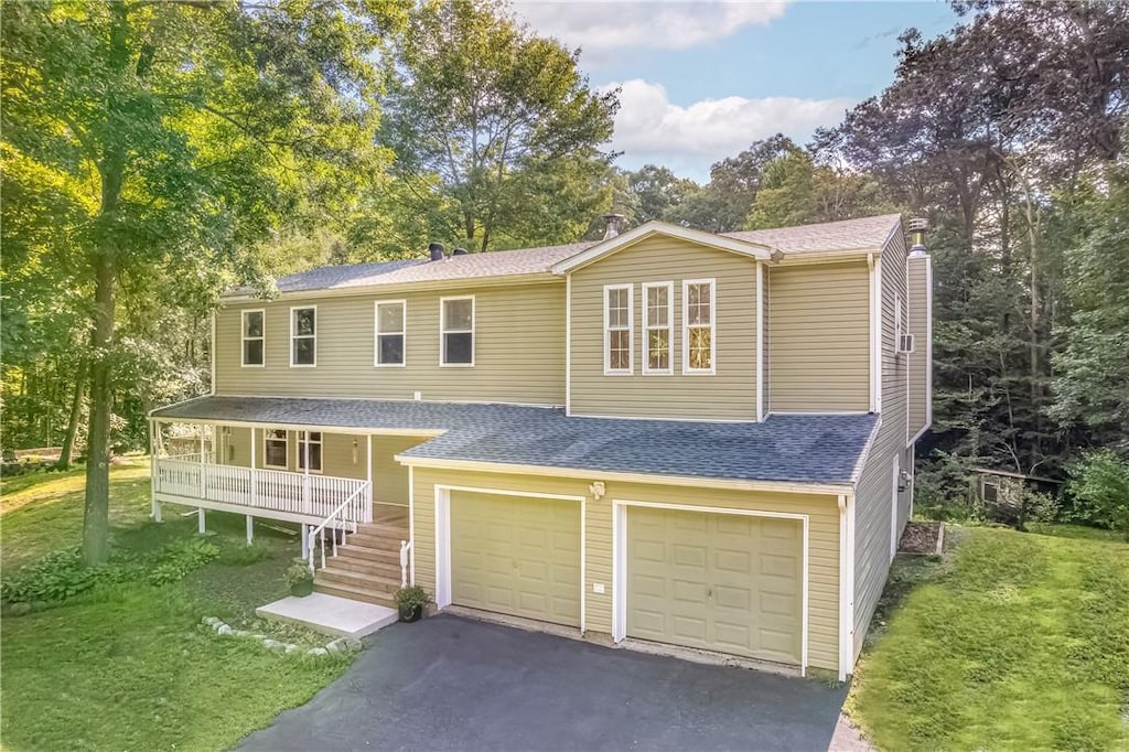 view of front of house with covered porch, a garage, and a front lawn