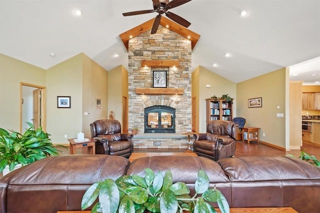 living area featuring vaulted ceiling, baseboards, ceiling fan, a stone fireplace, and wood finished floors