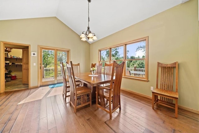 dining room featuring baseboards, a chandelier, vaulted ceiling, and light wood-style floors