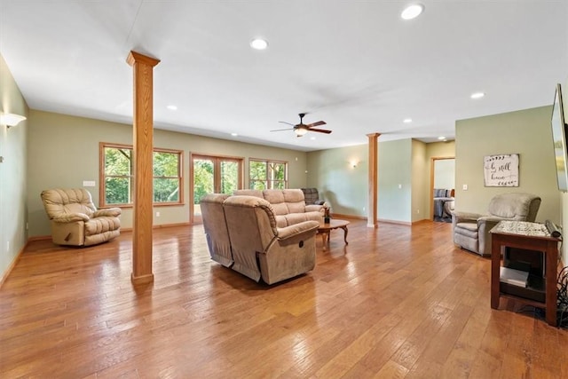 living area featuring a ceiling fan, light wood-style floors, and ornate columns