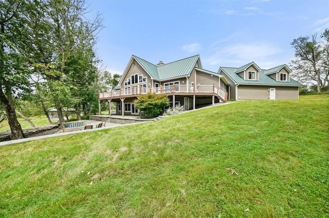 rear view of property with a patio area, a deck, a yard, and metal roof