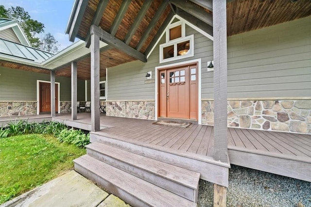 entrance to property featuring a standing seam roof, covered porch, and stone siding
