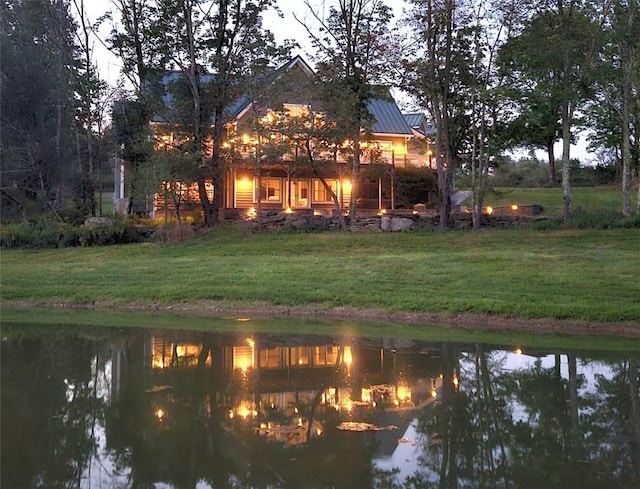 rear view of house with metal roof, a water view, a standing seam roof, and a yard