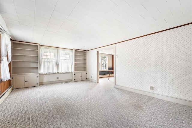 unfurnished living room with built in shelves, crown molding, and light carpet