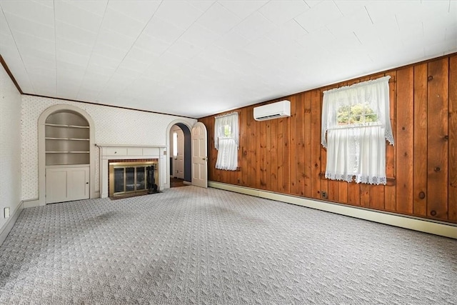 unfurnished living room featuring carpet, wood walls, a baseboard radiator, and a wall mounted AC