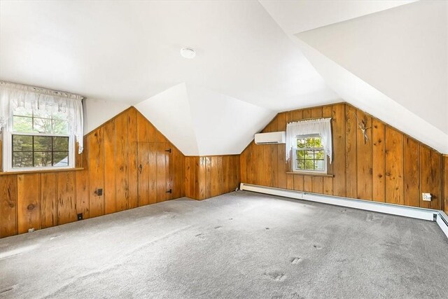 bonus room featuring carpet flooring, a wall mounted AC, a baseboard heating unit, lofted ceiling, and wood walls