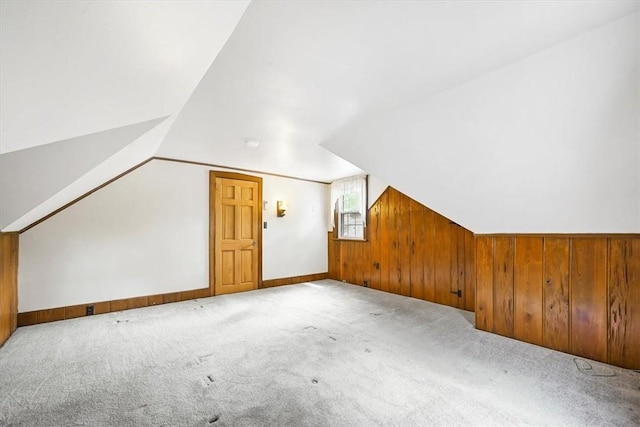 bonus room featuring wood walls, light colored carpet, and lofted ceiling