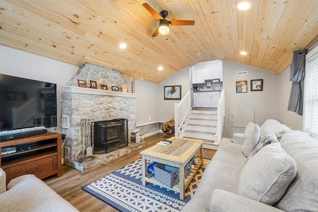 living room with lofted ceiling, a wood stove, wooden ceiling, ceiling fan, and light wood-type flooring