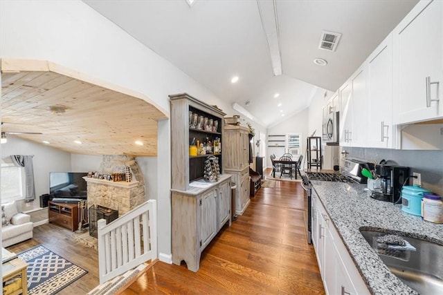 kitchen with white cabinets, dark hardwood / wood-style floors, lofted ceiling, and stainless steel appliances