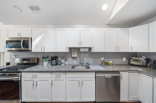 kitchen featuring light stone counters, sink, white cabinetry, and stainless steel appliances