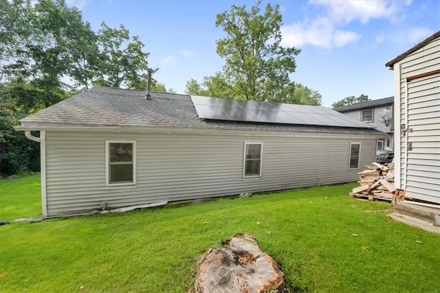 rear view of house featuring solar panels and a yard