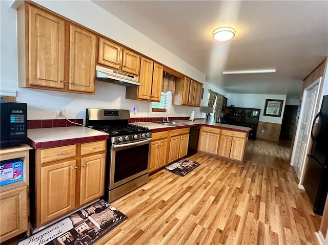 kitchen with sink, light wood-type flooring, tile counters, and black appliances