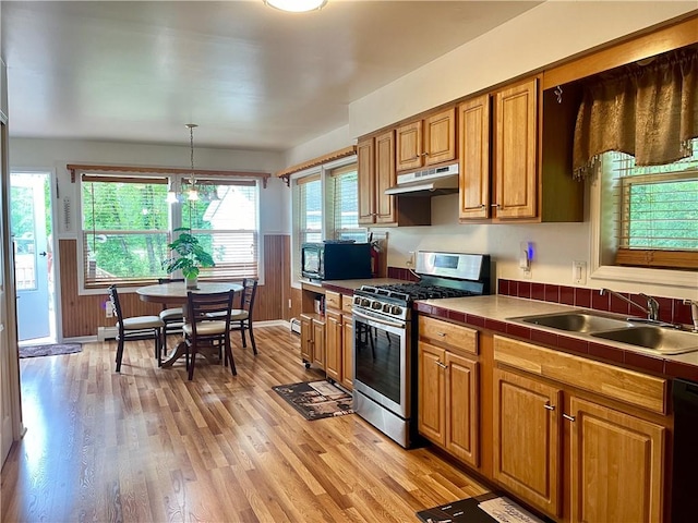 kitchen with light wood-type flooring, sink, black appliances, tile counters, and hanging light fixtures