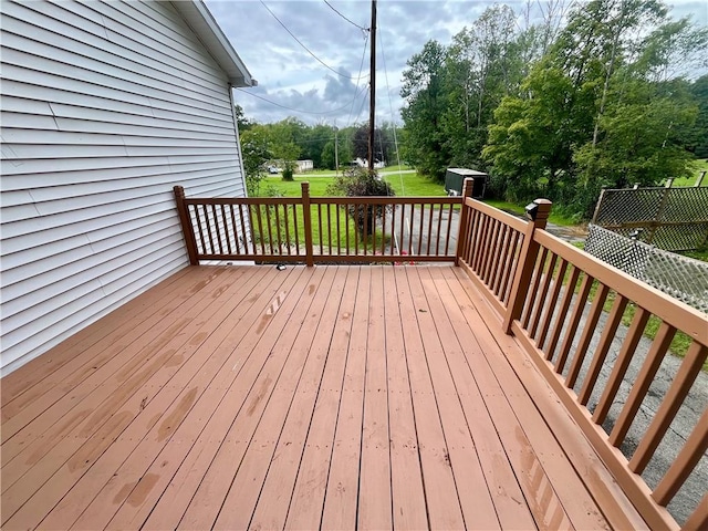 wooden deck featuring a storage unit and a lawn