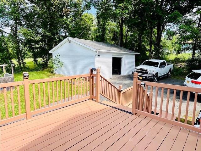 wooden deck featuring a lawn, an outdoor structure, and a garage