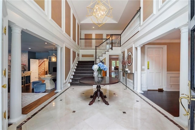 foyer entrance featuring a notable chandelier and decorative columns