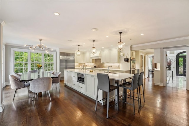 kitchen with a notable chandelier, white cabinetry, and pendant lighting