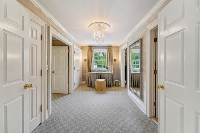 hall featuring an inviting chandelier, crown molding, and light colored carpet