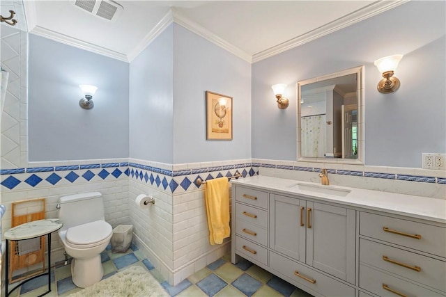 bathroom with toilet, vanity, tile walls, tile patterned floors, and crown molding