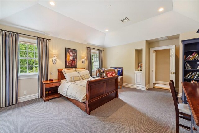 bedroom with light carpet, vaulted ceiling, and a raised ceiling