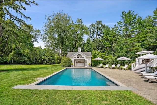 view of swimming pool with a patio area, a lawn, and an outdoor structure