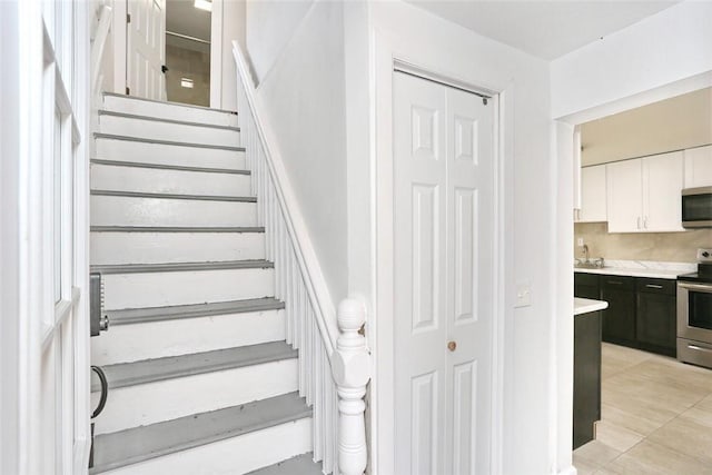 stairway with tile patterned floors and sink