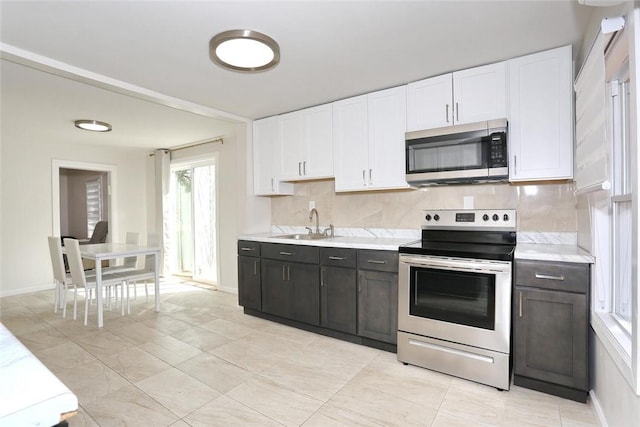 kitchen with white cabinets, sink, backsplash, and appliances with stainless steel finishes