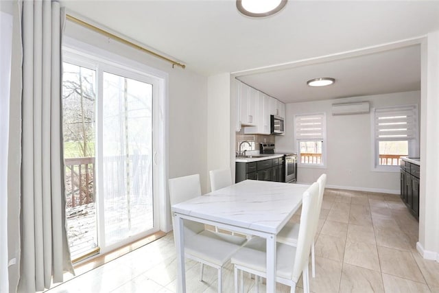 dining room featuring an AC wall unit, sink, and light tile patterned flooring