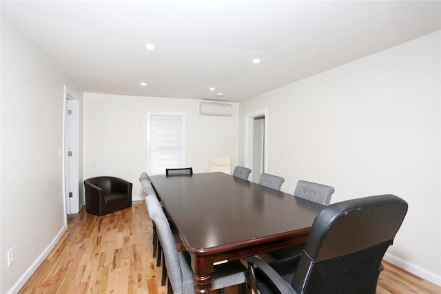 dining area with a wall unit AC and light hardwood / wood-style floors