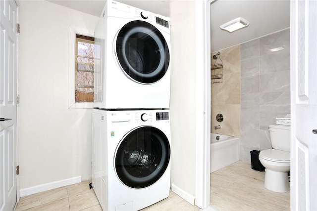 laundry area featuring stacked washer and dryer, light tile patterned floors, and tile walls