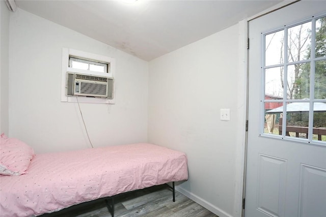 bedroom with cooling unit, wood-type flooring, lofted ceiling, and multiple windows